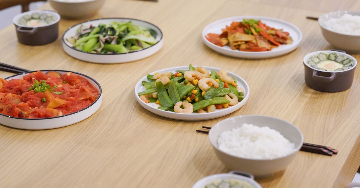 A variety of Asian dishes served on a wooden table, showcasing colorful and healthy ingredients.