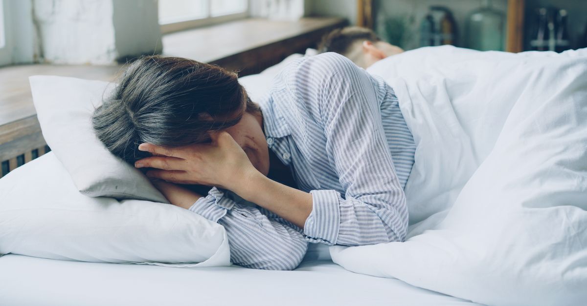 A woman in bed showing signs of anxiety. Soft light indoors.