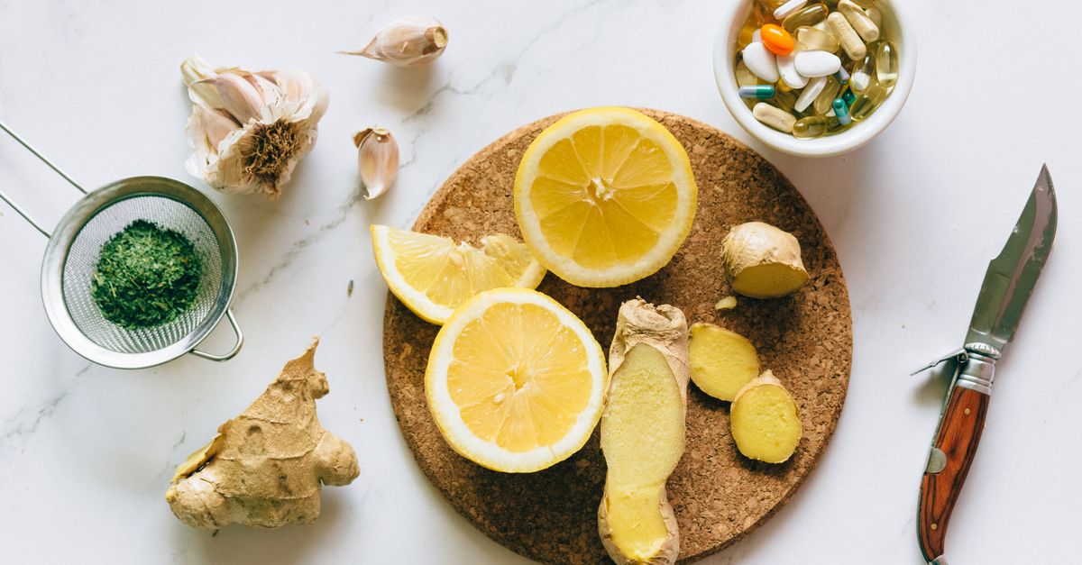 Flat lay of natural remedies including lemon, ginger, and garlic alongside pills.