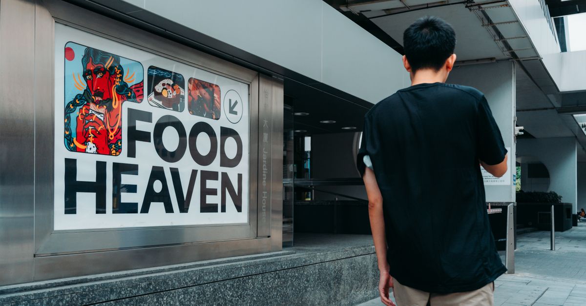 Man walking towards a colorful 'Food Heaven' sign in a modern urban setting.