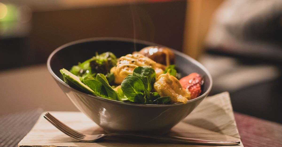 Delicious bowl of salad with fresh greens and grilled chicken served on a wooden platter.