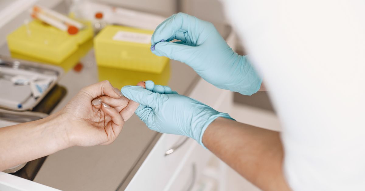 A healthcare professional wearing gloves takes a blood sample from a patient. Medical setting.