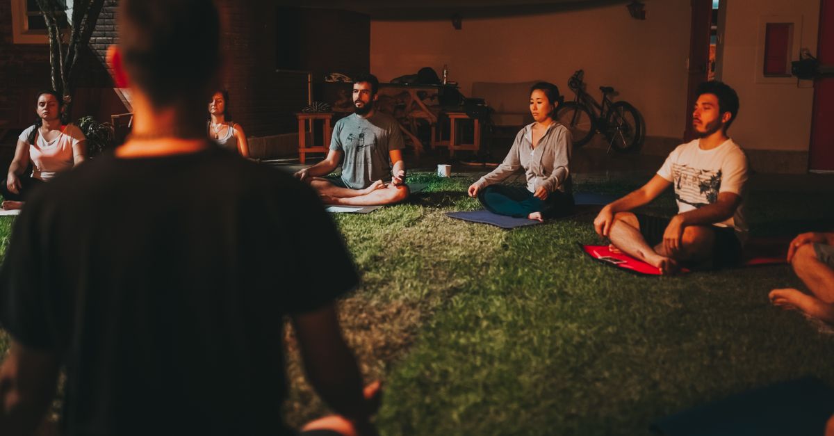A diverse group of people meditating outdoors on a summer night.