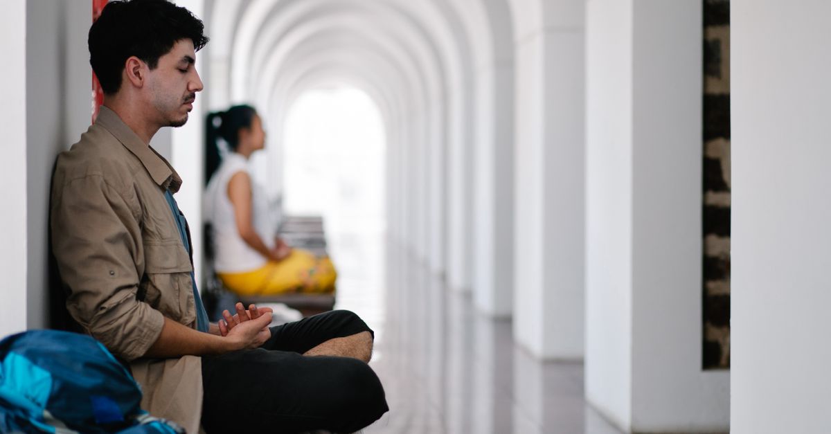 Man and woman meditate in a serene corridor, emphasizing relaxation.