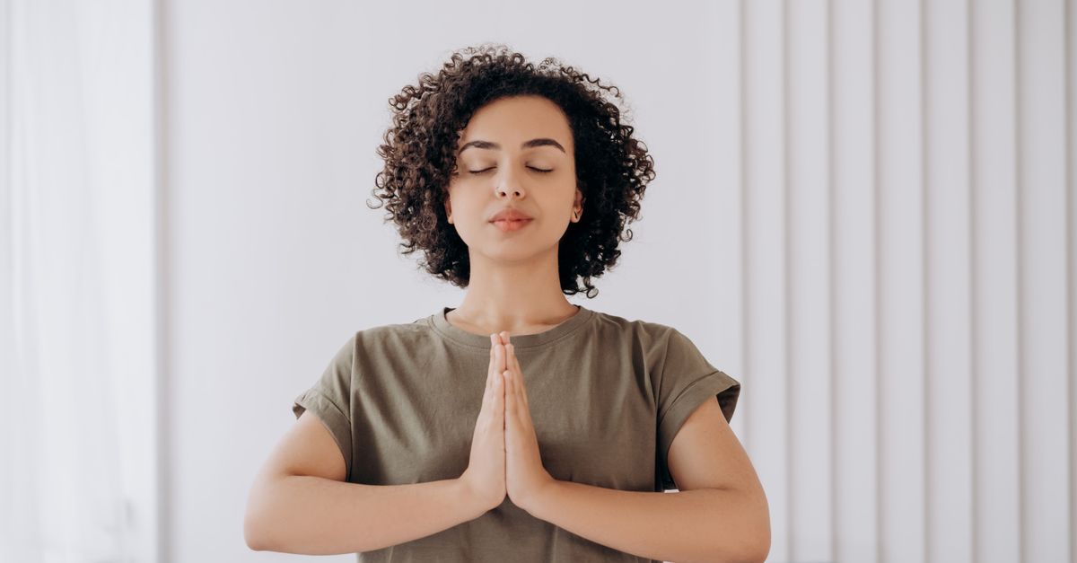 A young woman with closed eyes meditating indoors, embodying tranquility and inner peace.