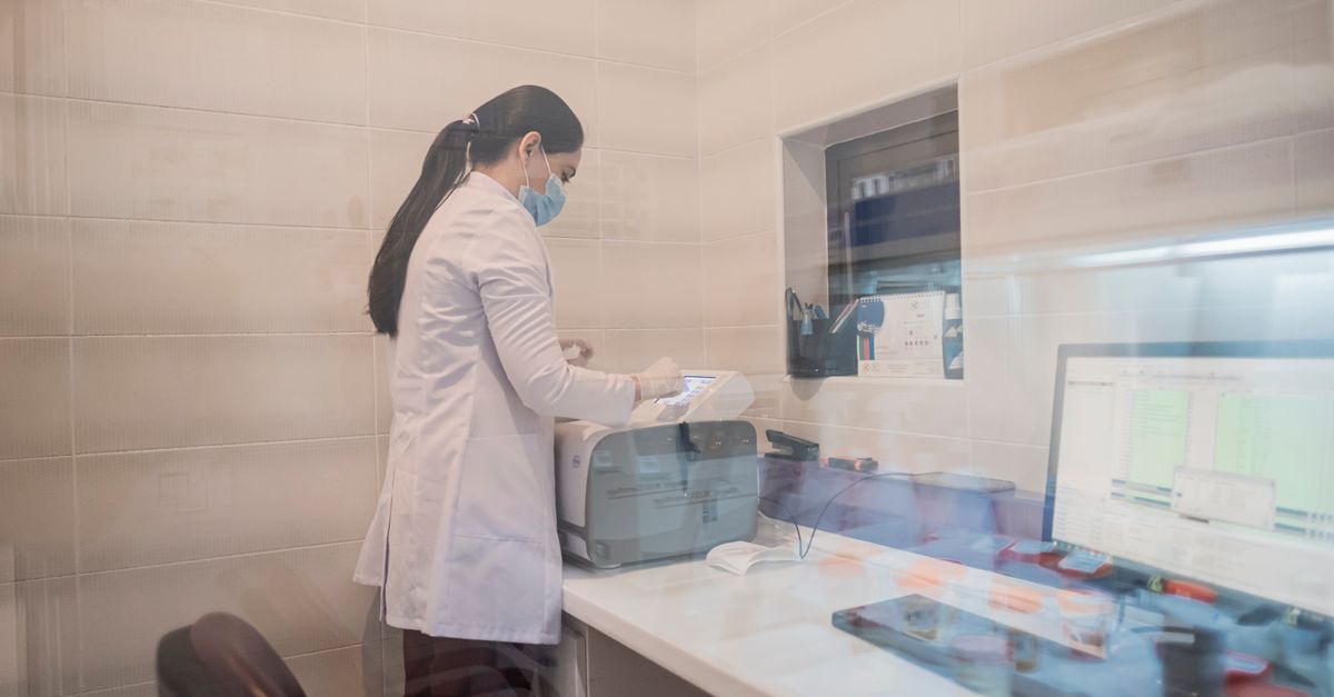 Woman in a lab coat examines equipment in a laboratory environment, Baku, Azerbaijan.