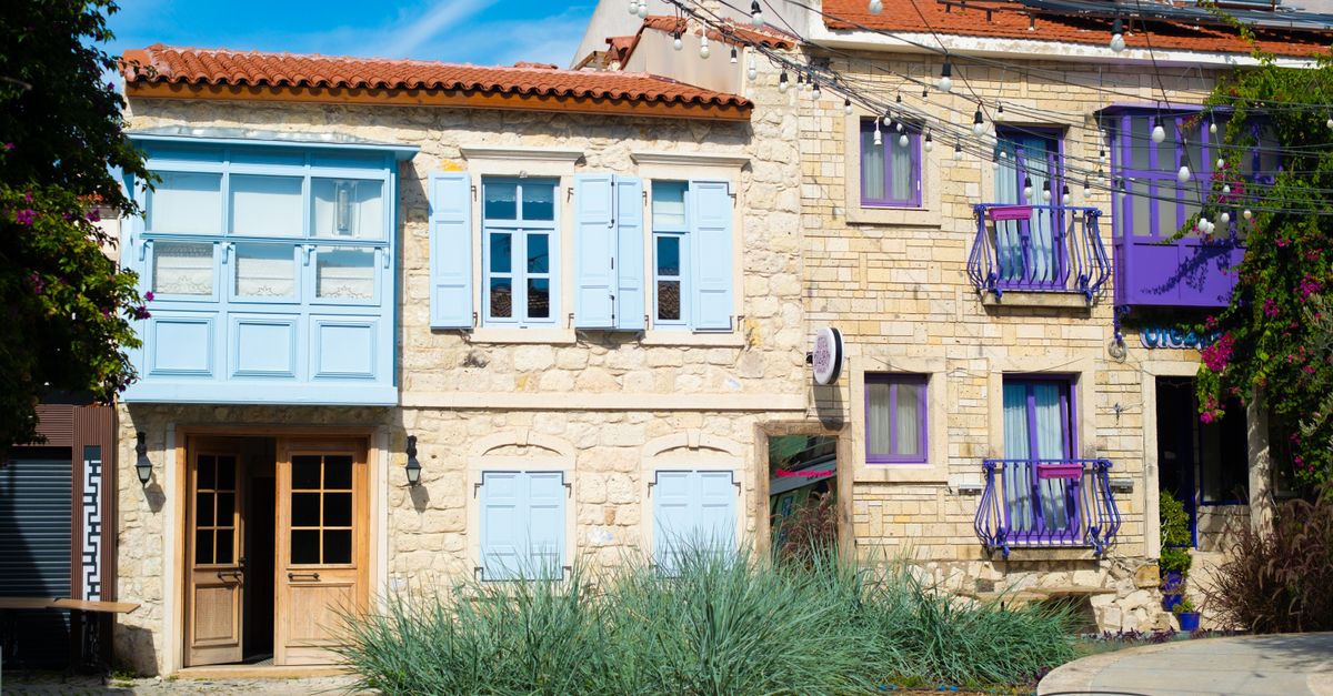 Colorful stone houses with blue and purple accents in Alaçatı, İzmir, Türkiye.