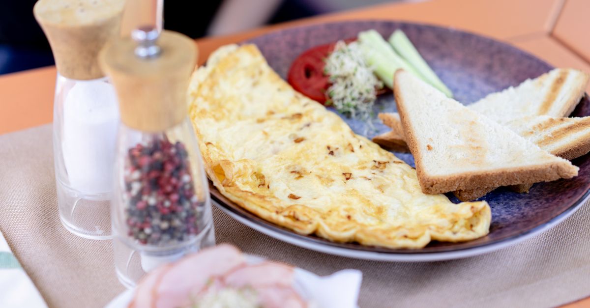 A nicely plated omelette breakfast with toast, cucumbers, and spices. Perfect start to the day.