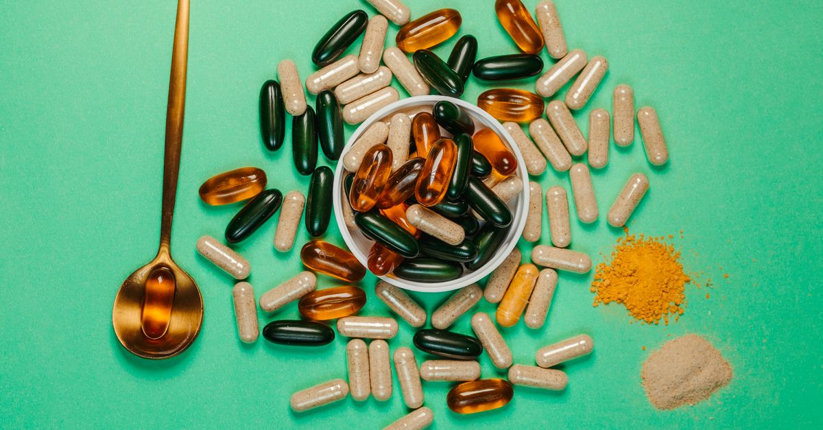 A vibrant assortment of capsules and powders on a green background with a golden spoon.