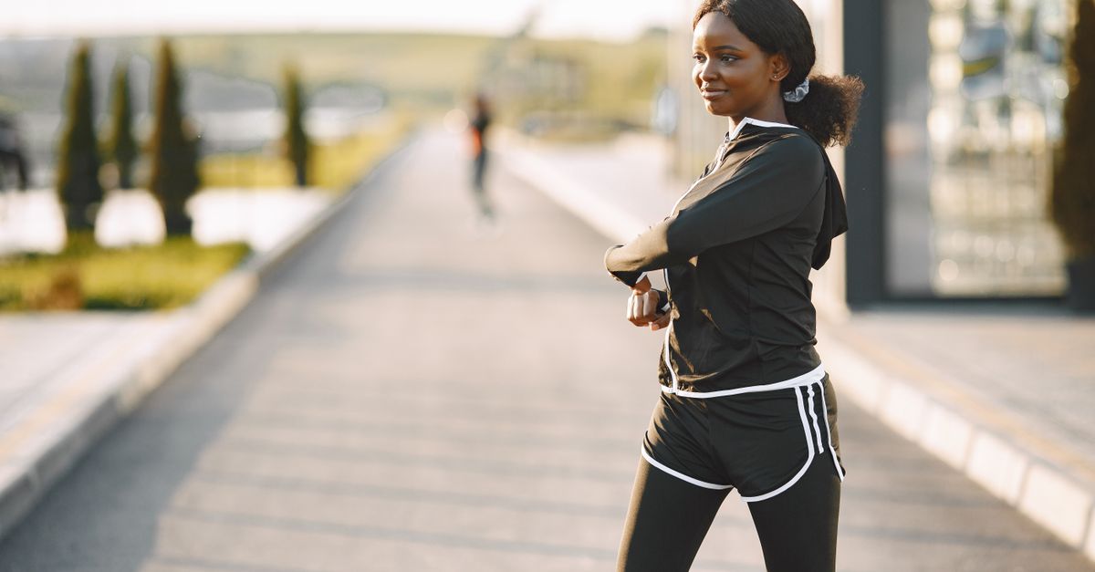Woman in activewear stretches on a sunny morning outdoors, promoting wellness.