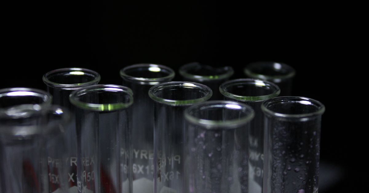 Glass test tubes with condensation in a dark lab environment.