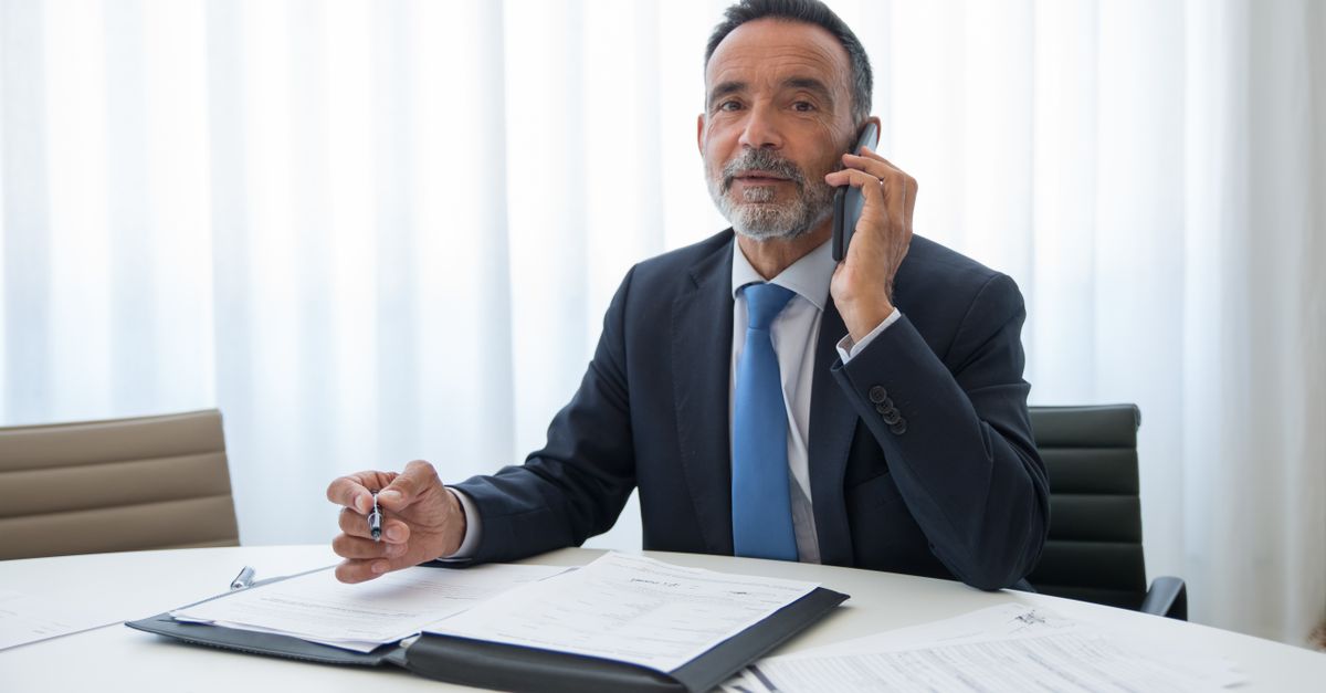Senior businessman in suit discussing important documents on the phone at an office room.