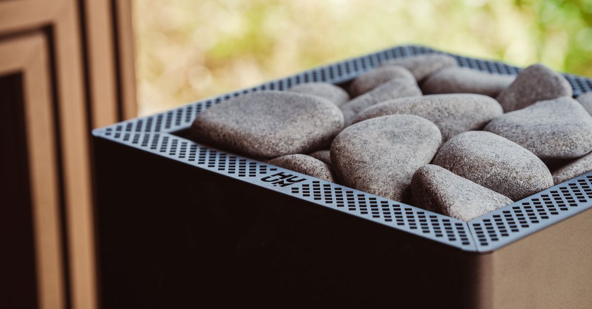 Close-up of a modern sauna heater showcasing smooth stones and minimalist design.