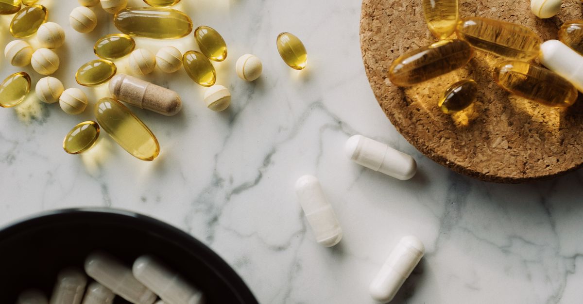 Flat lay of various capsules and pills on marble for healthcare and medication concept.