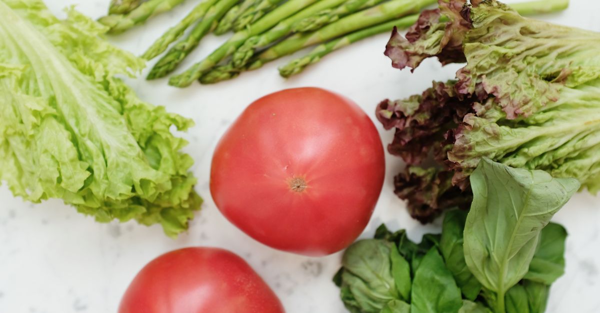 Top view of fresh asparagus, lettuce, basil, and tomatoes, highlighting healthy and nutritious ingredients.