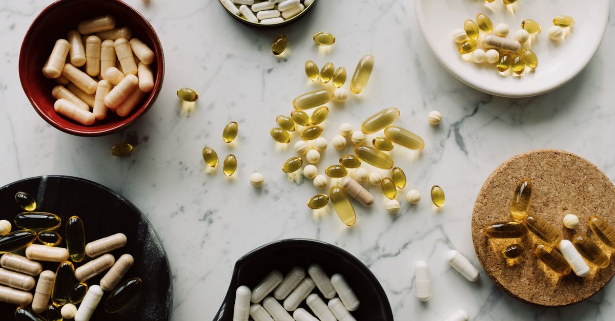Variety of capsules and pills displayed in bowls on a marble table, ideal for healthcare concepts.