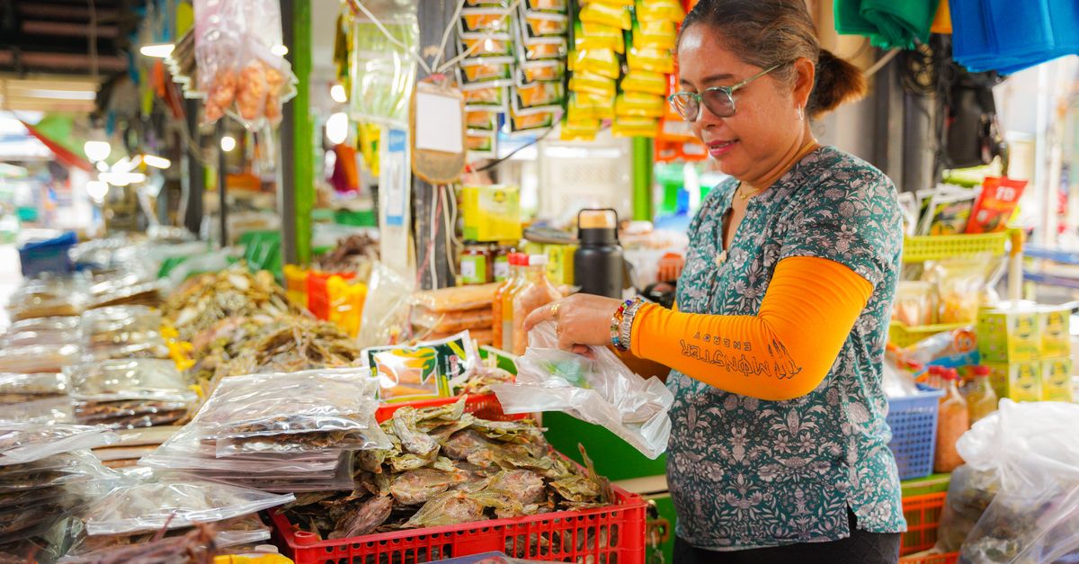 A woman selecting dried fish at a bustling market in Central Visayas, Philippines.