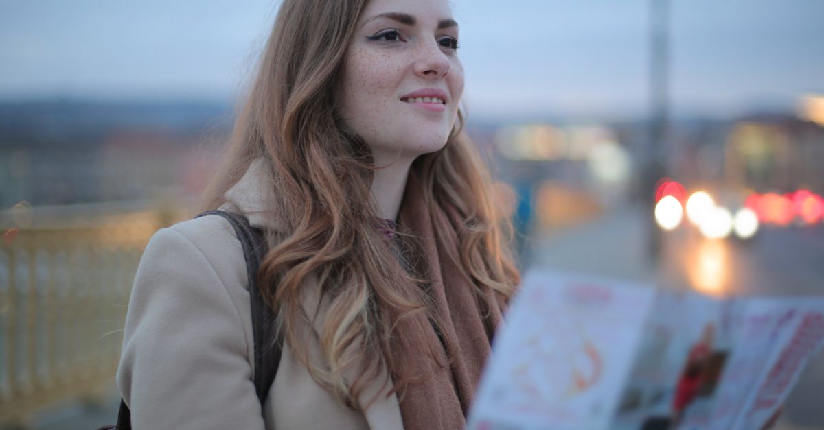 Smiling woman with a map enjoying a travel adventure outdoors.
