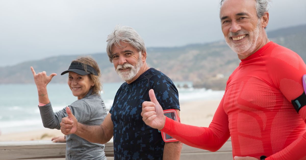 Smiling senior friends exercising on a beach in Portugal, embracing a healthy lifestyle.