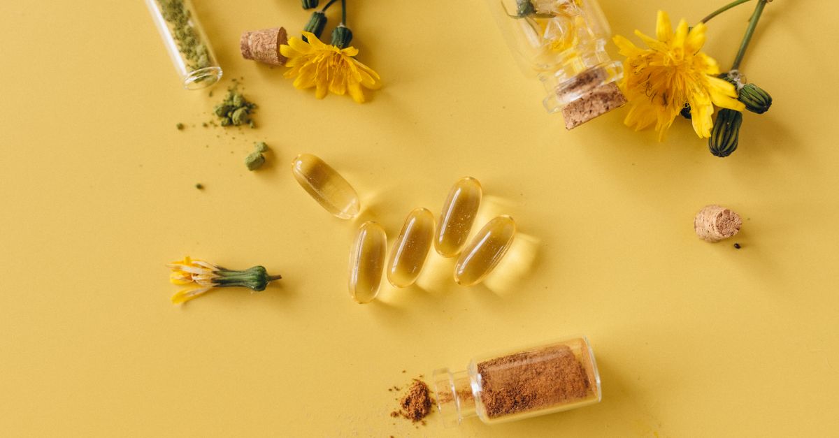 Flat lay of herbal supplements, dandelion flowers, and test tubes on a yellow background.