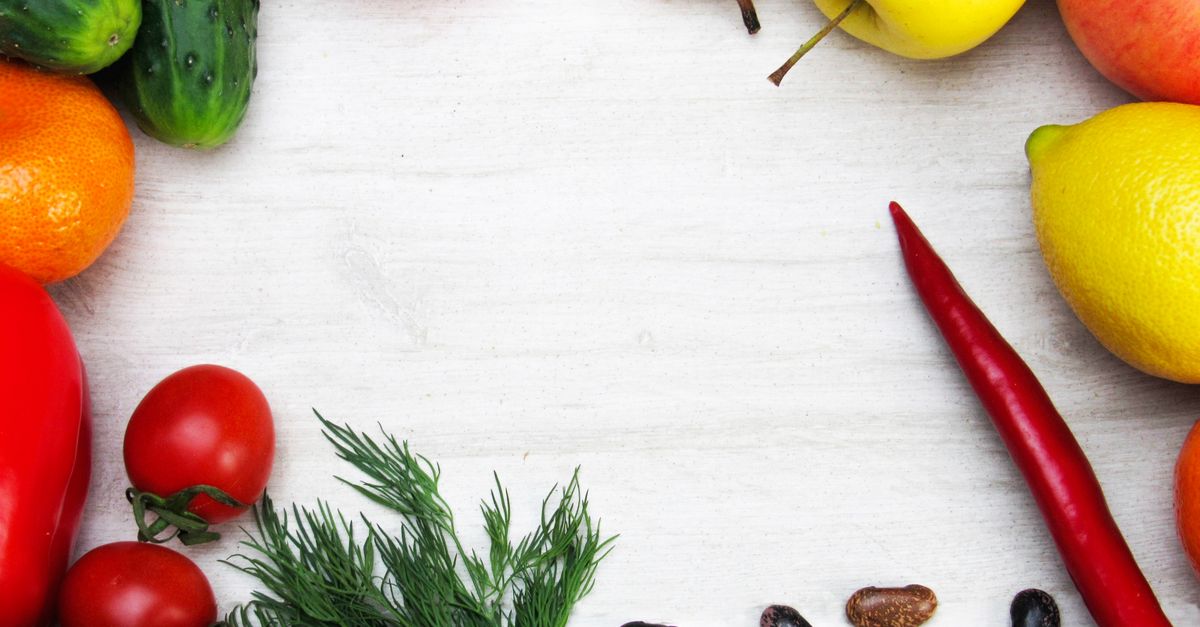 A vibrant flat lay of fresh fruits and vegetables with ample copy space on a white background.