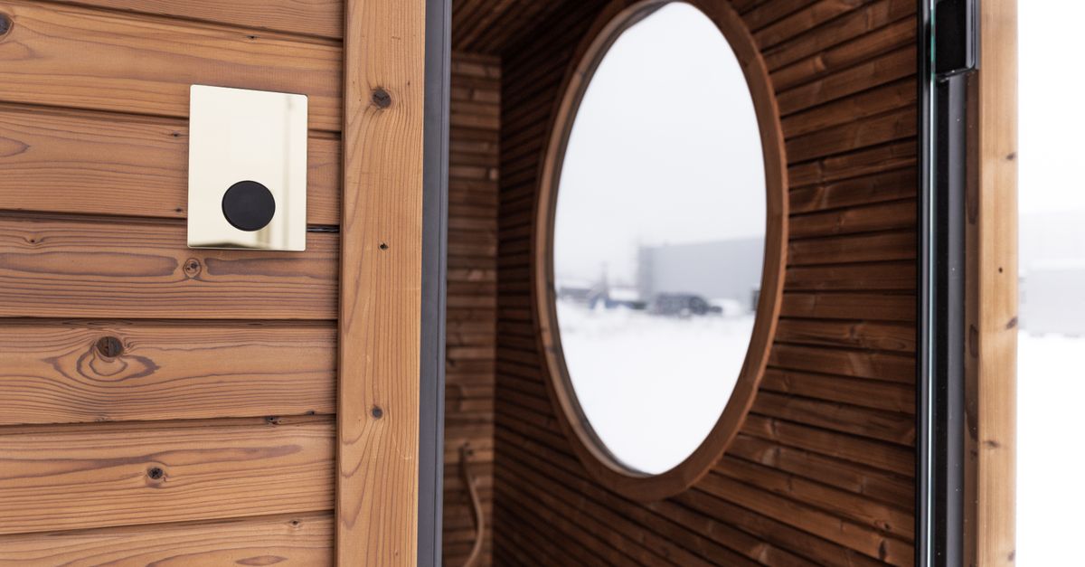 A contemporary wooden sauna cabin featuring a sleek circular window and digital controller.