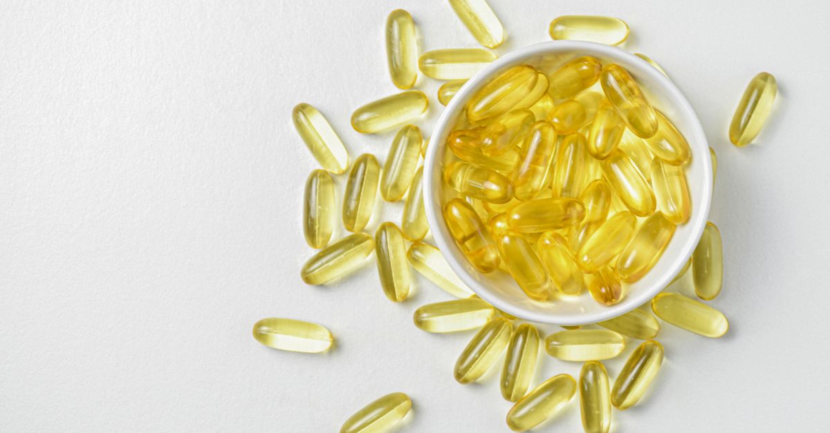 High-angle shot of omega-3 fish oil capsules in a ceramic bowl on a white background.