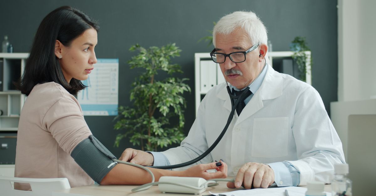 Doctor checking blood pressure of patient at medical clinic.