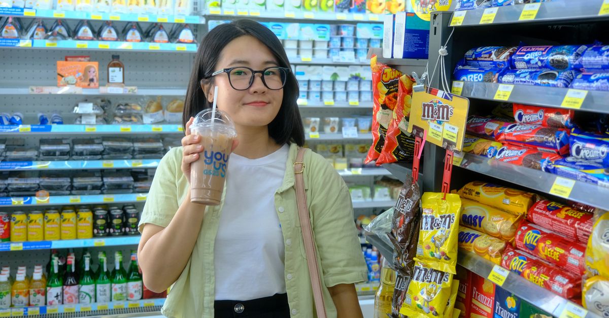 A young woman enjoys a drink while shopping in a convenience store in Hue City, Vietnam.