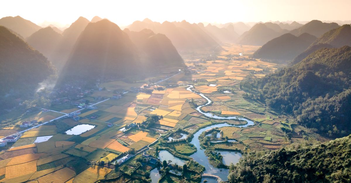 A breathtaking aerial view of farmland and mountains under sunrise, showcasing nature's beauty.