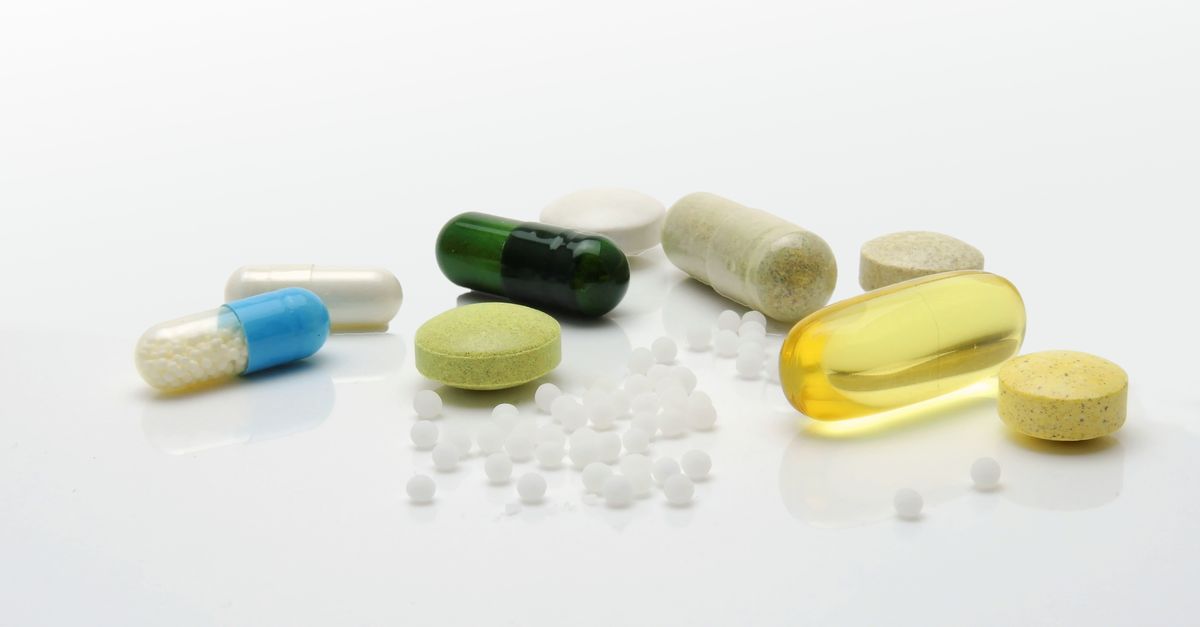 Close-up of various pills and capsules on a white surface, representing healthcare.