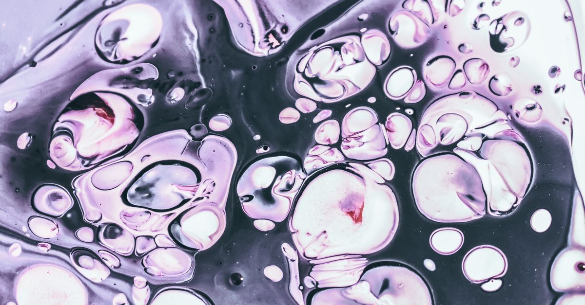 From above closeup of wet mixed purple paint with bubbles on glossy surface as abstract background