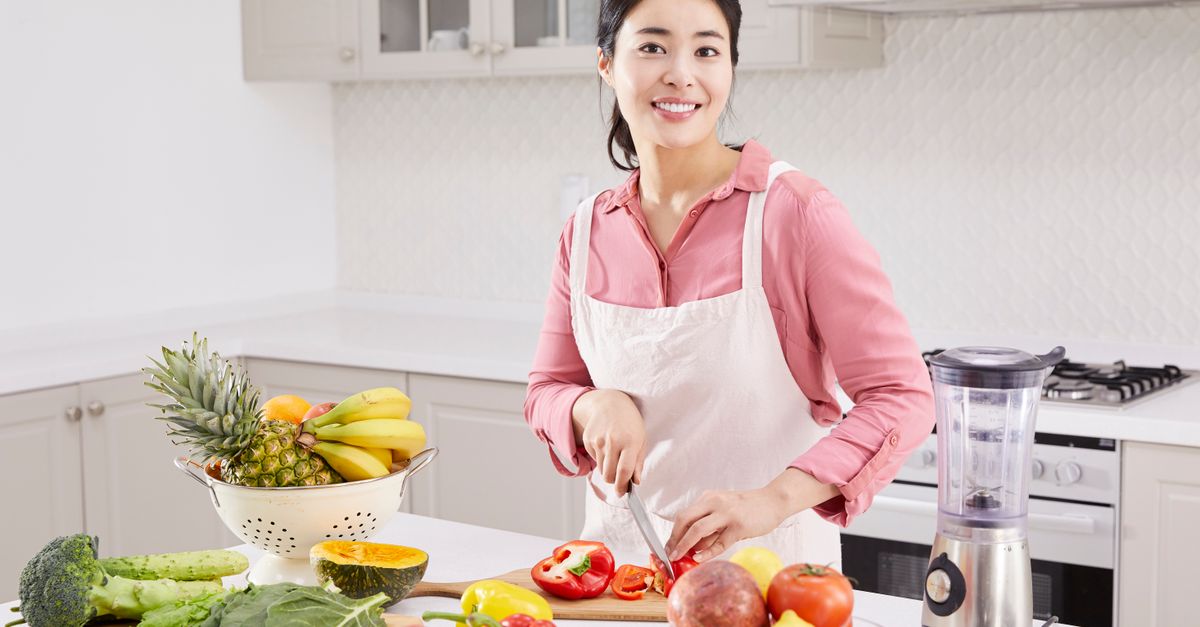 Woman slicing vegetables in kitchen, showcasing healthy living and cooking lifestyle.
