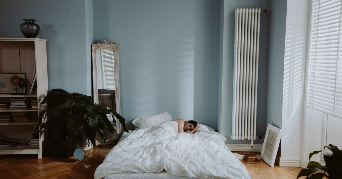 Woman sleeping peacefully in a cozy and stylish bedroom with soft natural light.