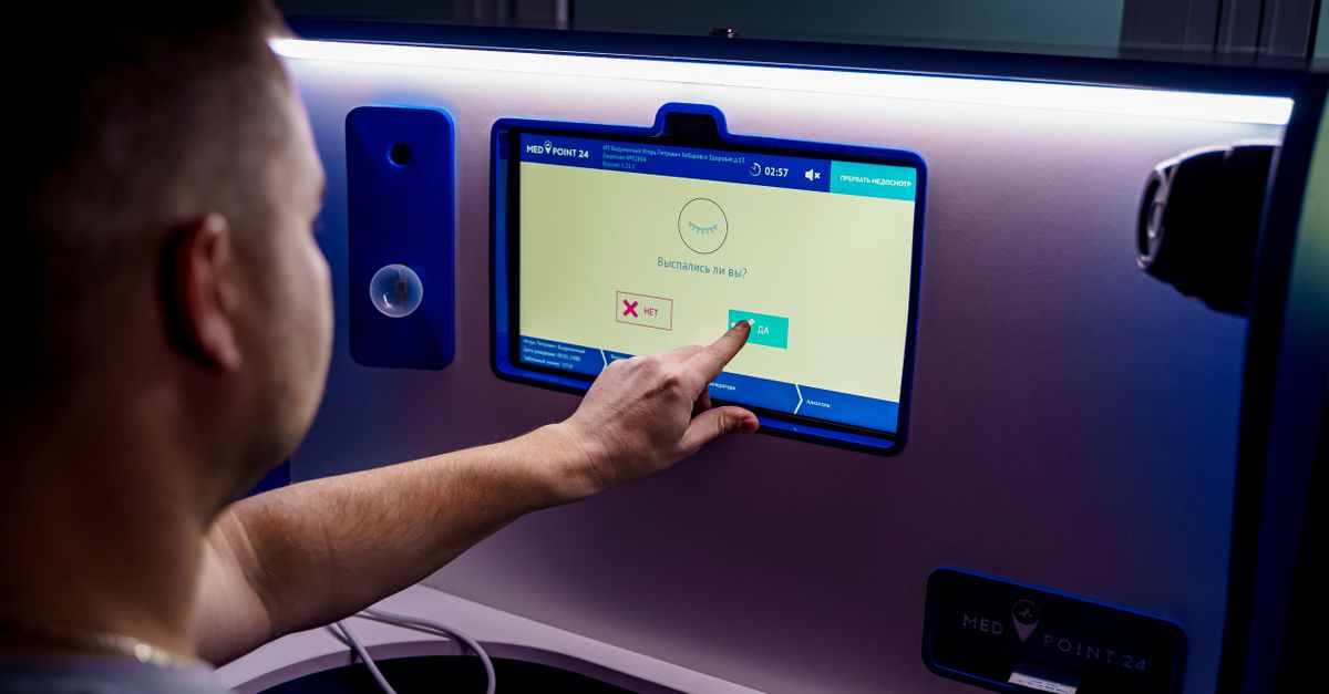 A man interacts with a touchscreen kiosk for telemedicine services, emphasizing modern healthcare technology.