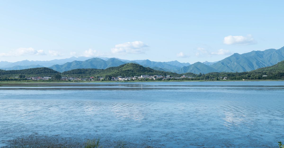 A serene lake with a mountain backdrop under a clear blue sky, perfect for nature lovers.