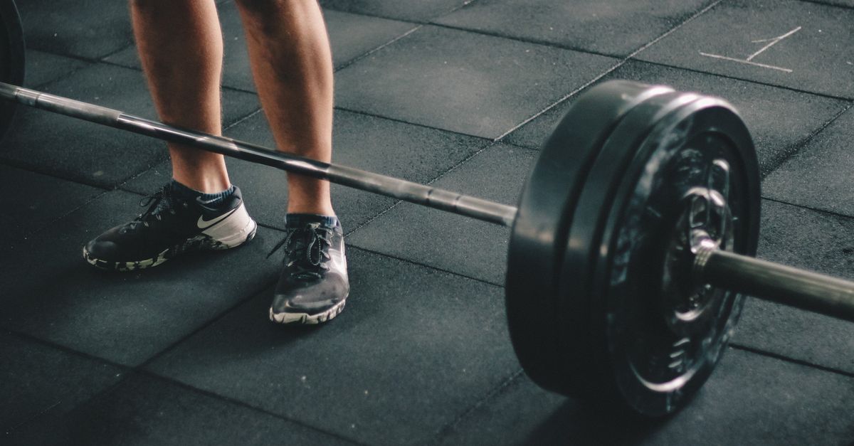 Close-up of a man deadlifting a heavy barbell in an indoor gym setting.