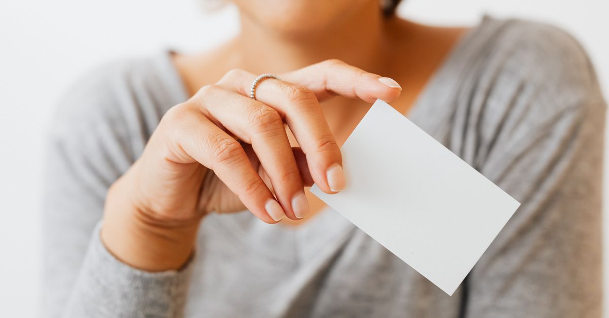 A woman in gray sleeves holding a blank business card, perfect for presentation or mockup use.