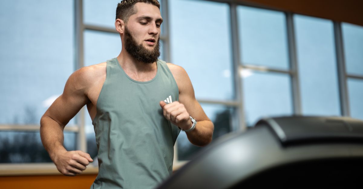 Fit young man exercising on a treadmill indoors, focused and determined.