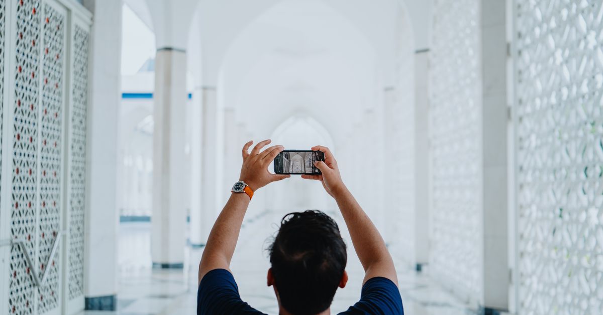 Person photographing Shah Alam Mosque interior, showcasing stunning Islamic architecture.