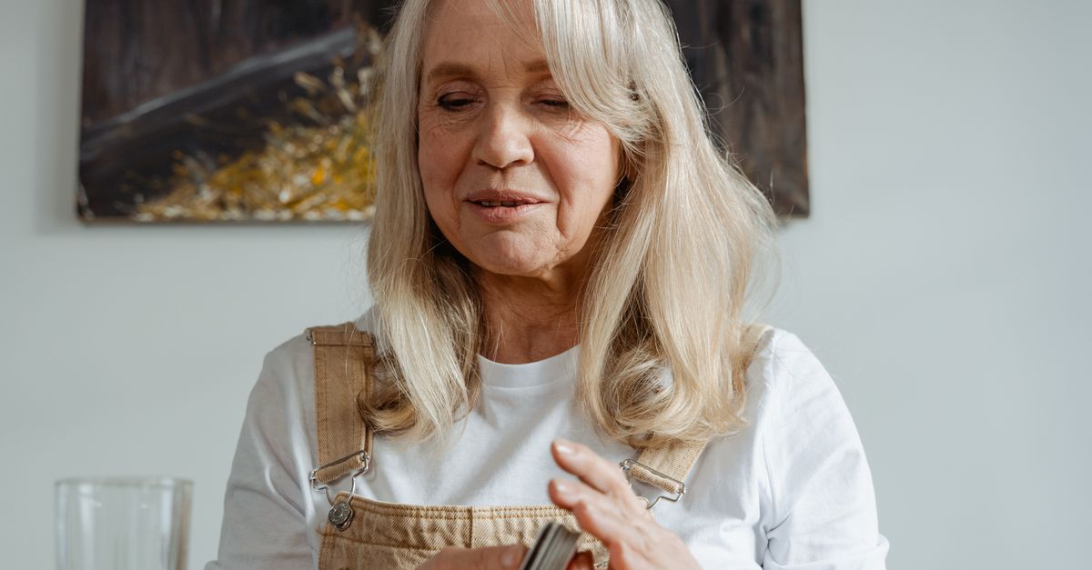 Cheerful senior woman playing cards at home, enjoying a relaxing moment.