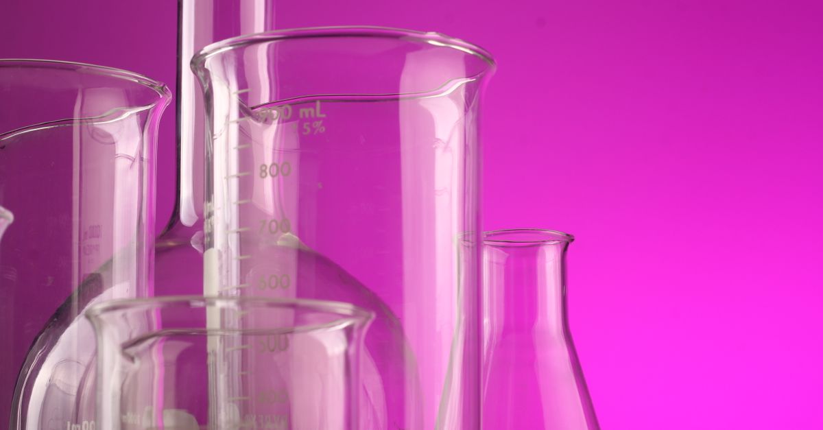 Clear glass laboratory flasks with volume measurements against a vibrant purple backdrop, ideal for science themes.