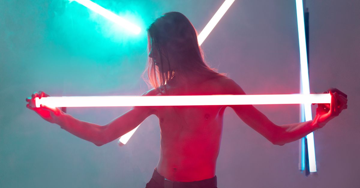 Shirtless person illuminated by vibrant neon lights, creating a futuristic and artistic aura.