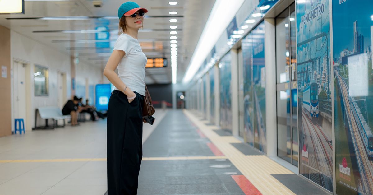 Woman in casual attire waiting at a modern metro station platform.
