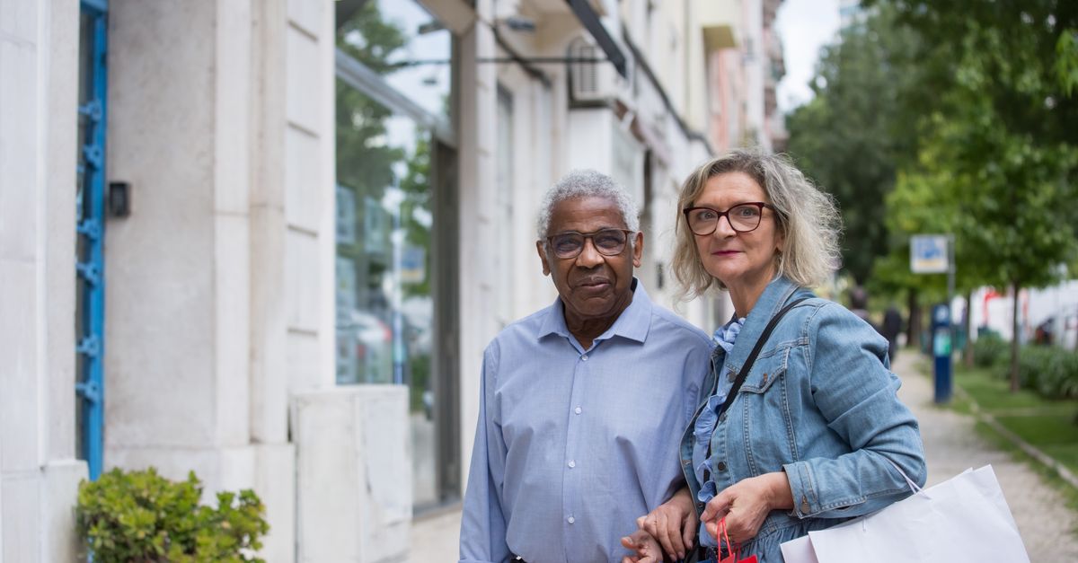 Elderly couple holding shopping bags on a sunny day in Portugal, enjoying leisure time.