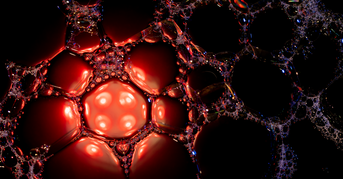 Close-up of soapy bubbles with red and black highlights, showcasing a dramatic abstract texture.