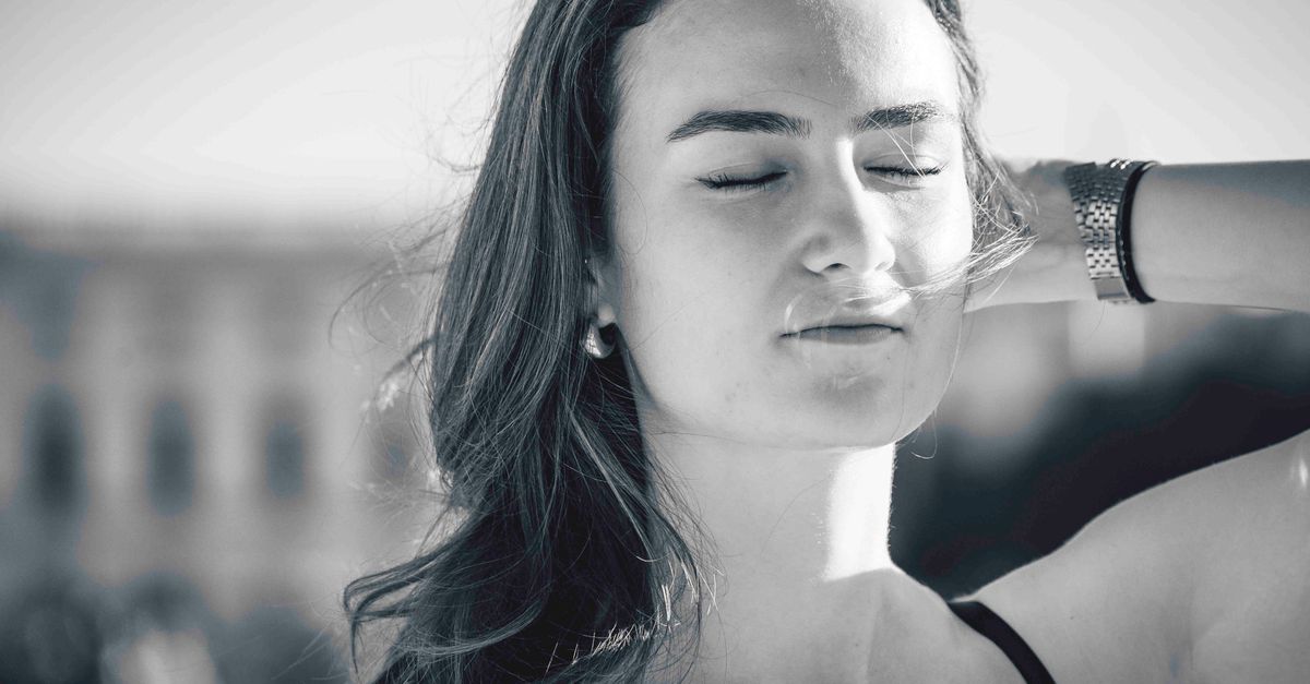 Black and white portrait of a woman with closed eyes enjoying sunlight in Berlin.