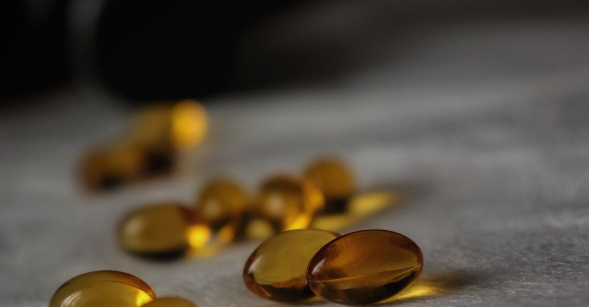 Close-up of golden soft gel capsules with a dark blurred background.