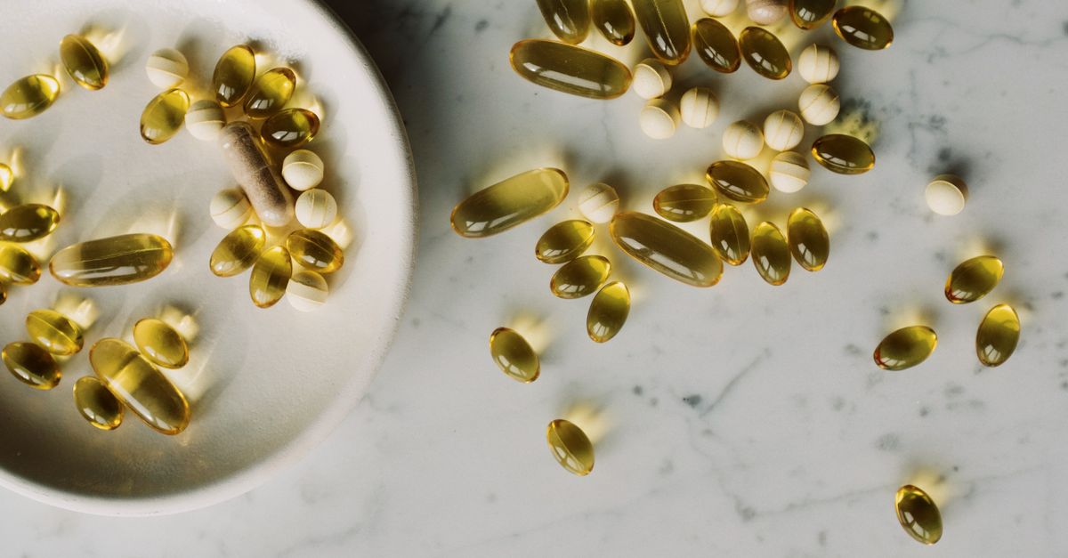 Top view of gelatin coated multivitamin pills placed on marble tabletop near plate with various drugs in studio at day time