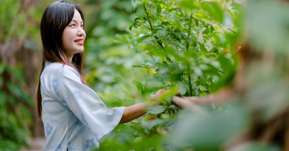 A young woman enjoys the tranquility of a verdant garden, surrounded by greenery.